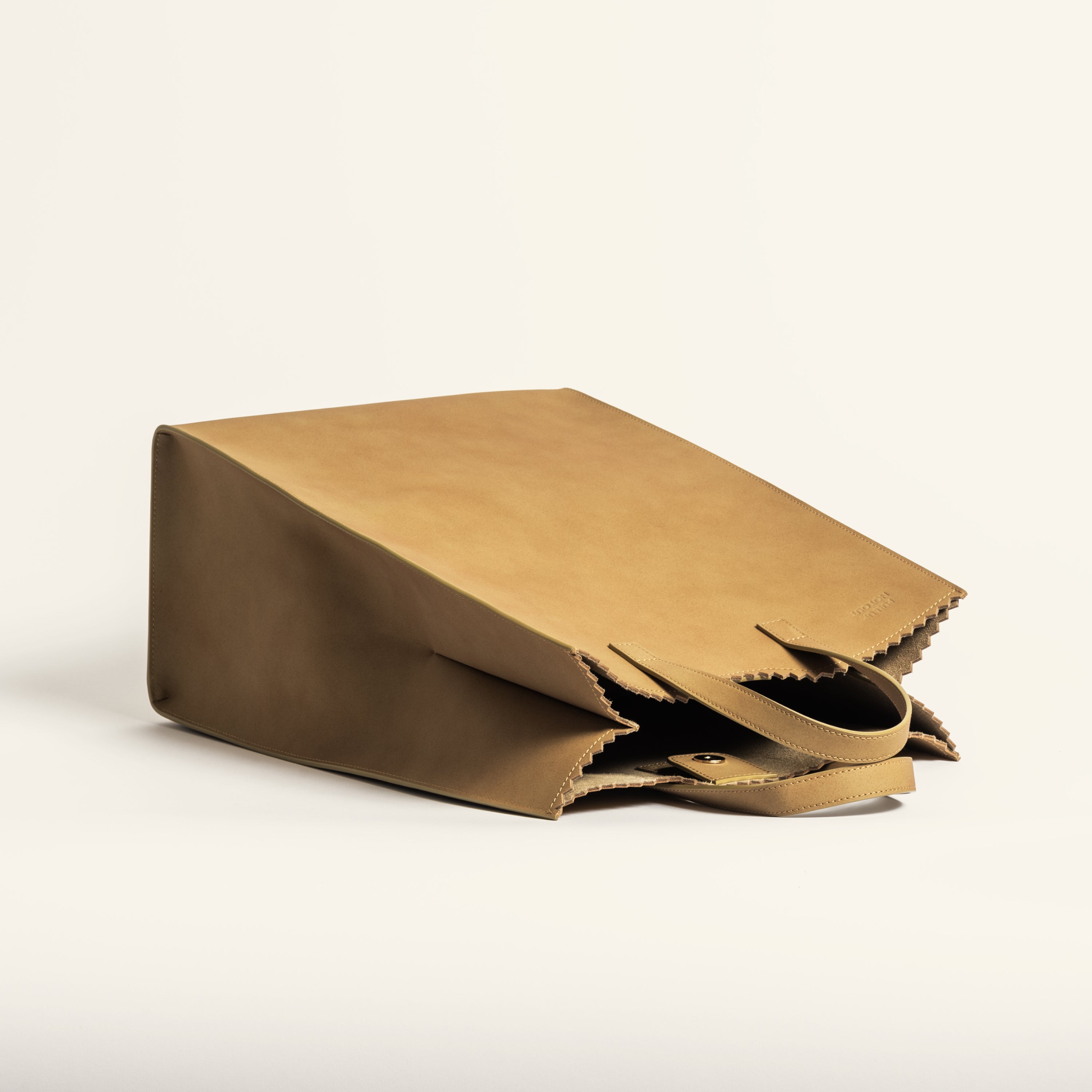 Kami tote bag by bukuro. A leather paper grocery bag tipped over on white backdrop.