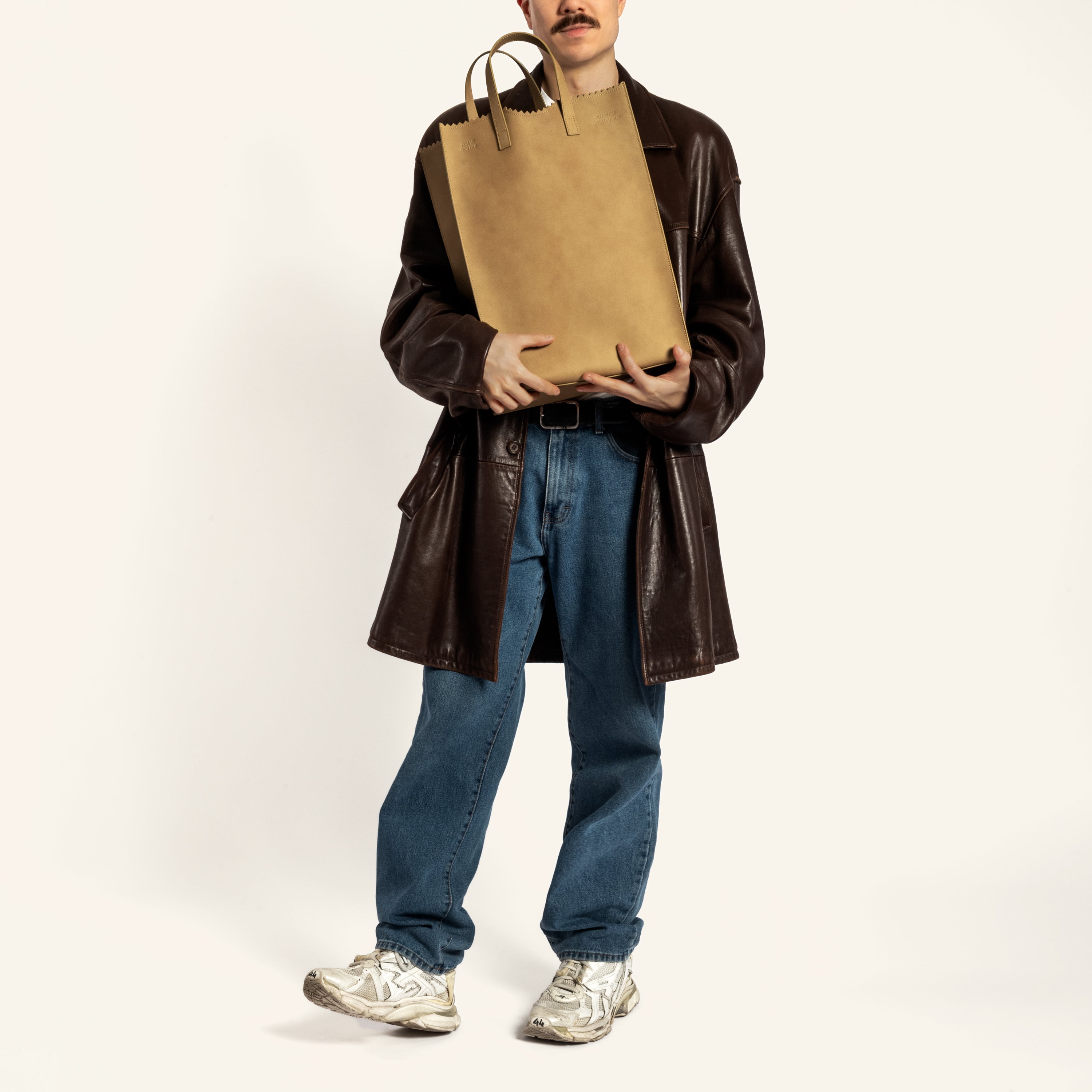 Japanese male model holding Kami tote bag by bukuro. A leather paper grocery bag held by a Japanese male model.